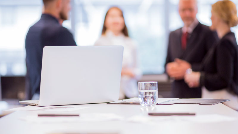glass water with laptop table front businesspeople background